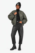 LARNA Bomberjacke in Green Frost, offen getragen mit JEANY Baggy Jeans in Faded Black, schwarzem Rollkragen, Mütze und Boots.