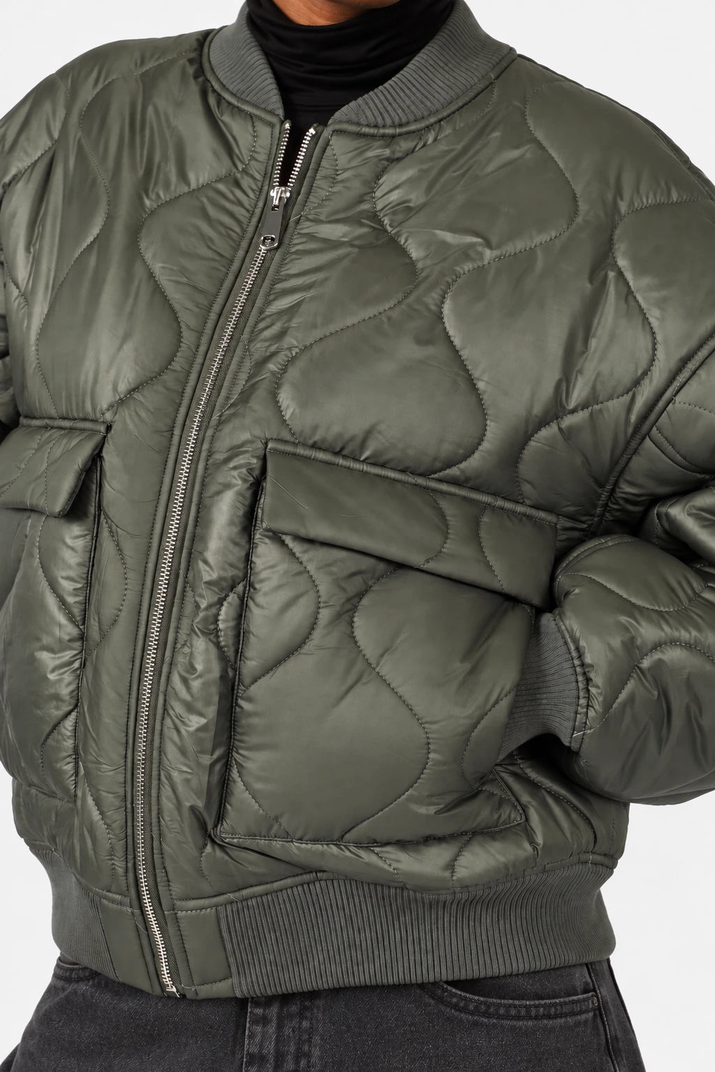LARNA Padded Winter-Bomberjacke in Green Frost, Detailaufnahme von Steppung, Pattentasche, Reißverschluss und Rippbündchen.