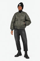 LARNA Padded Winter-Bomberjacke in Green Frost, geschlossene Ganzkörperansicht mit JEANY Baggy Jeans in Faded Black und schwarzen Boots.