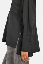 LEA.K Loose Fit Bluse in Schwarz, Detail von Manschette, Seitenschlitz und Logoanhänger mit JEANY Moonlight